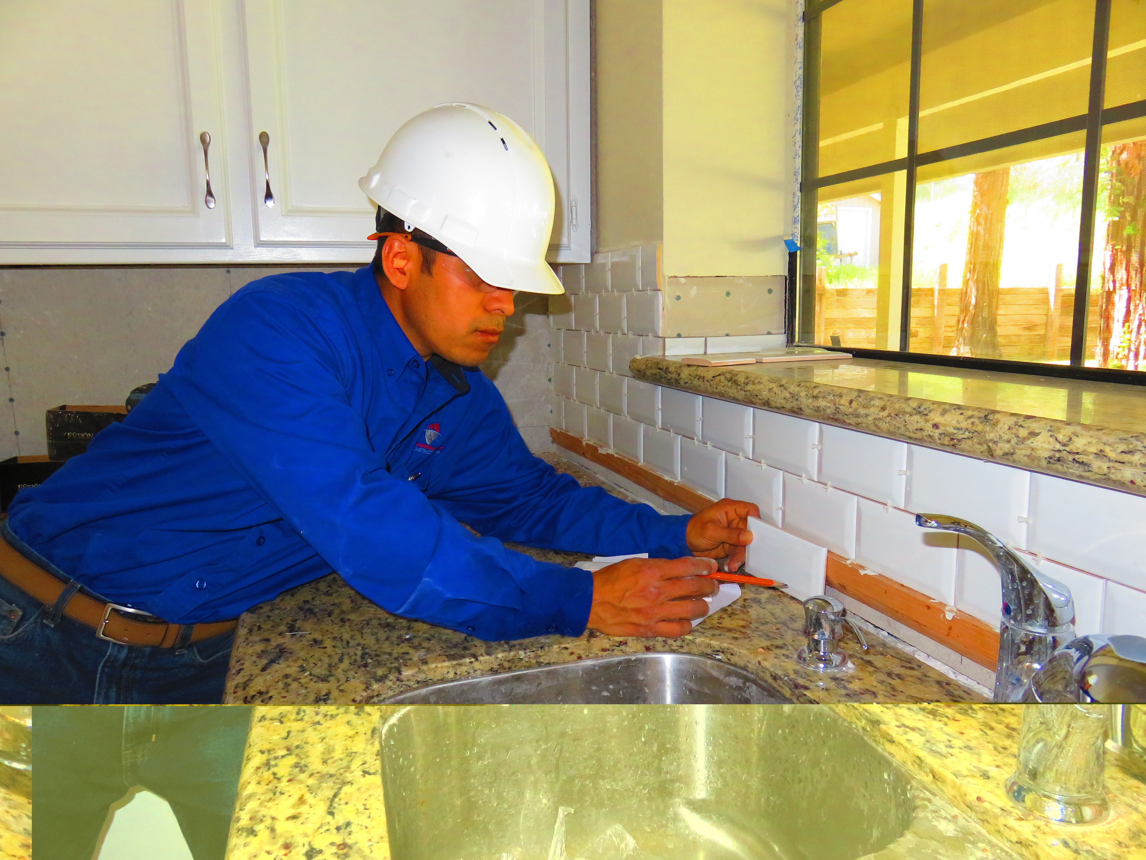 Construction worker installing kitchen backsplash — HCIC
